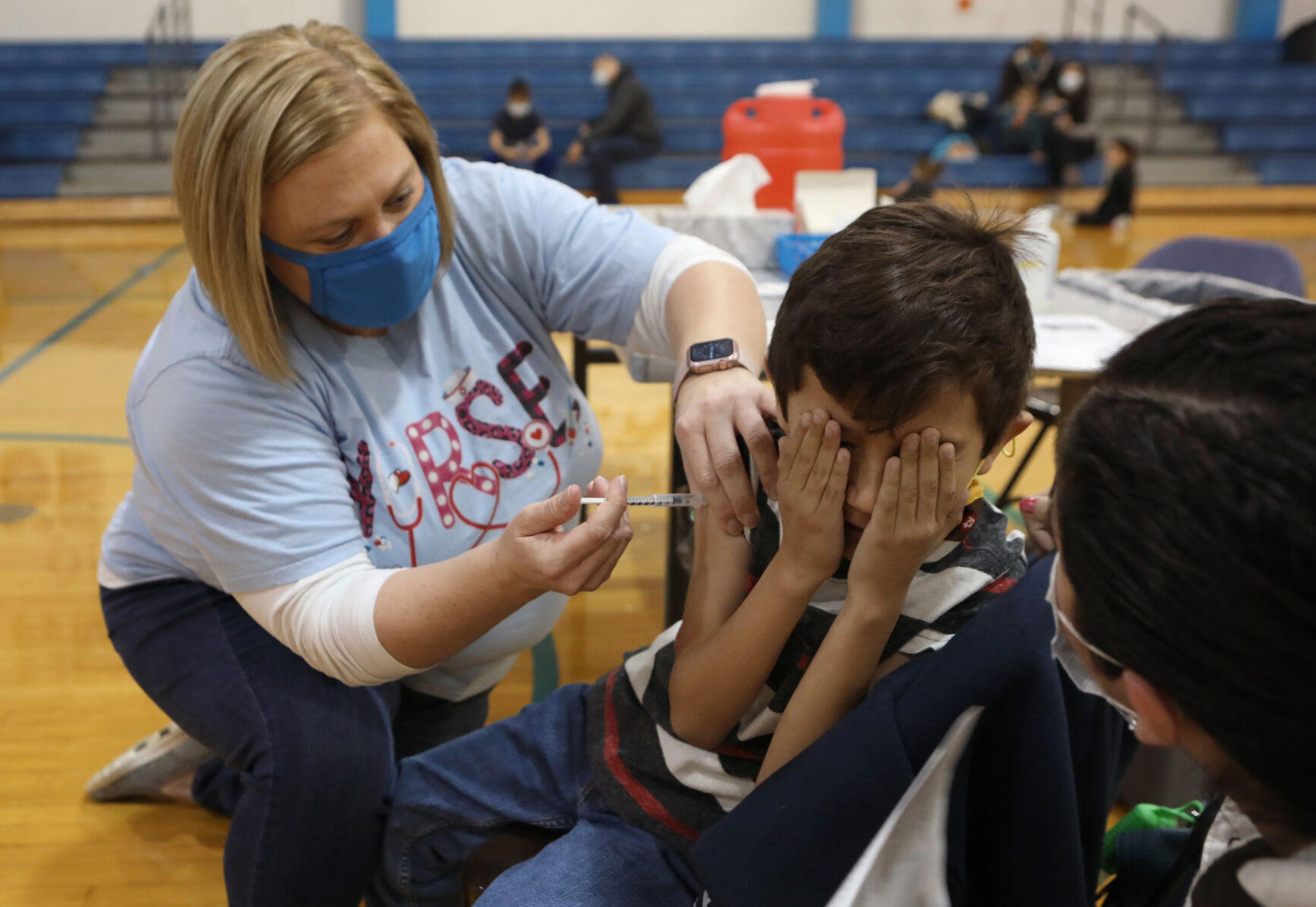 Alek Tarango covers his eyes during his vaccination